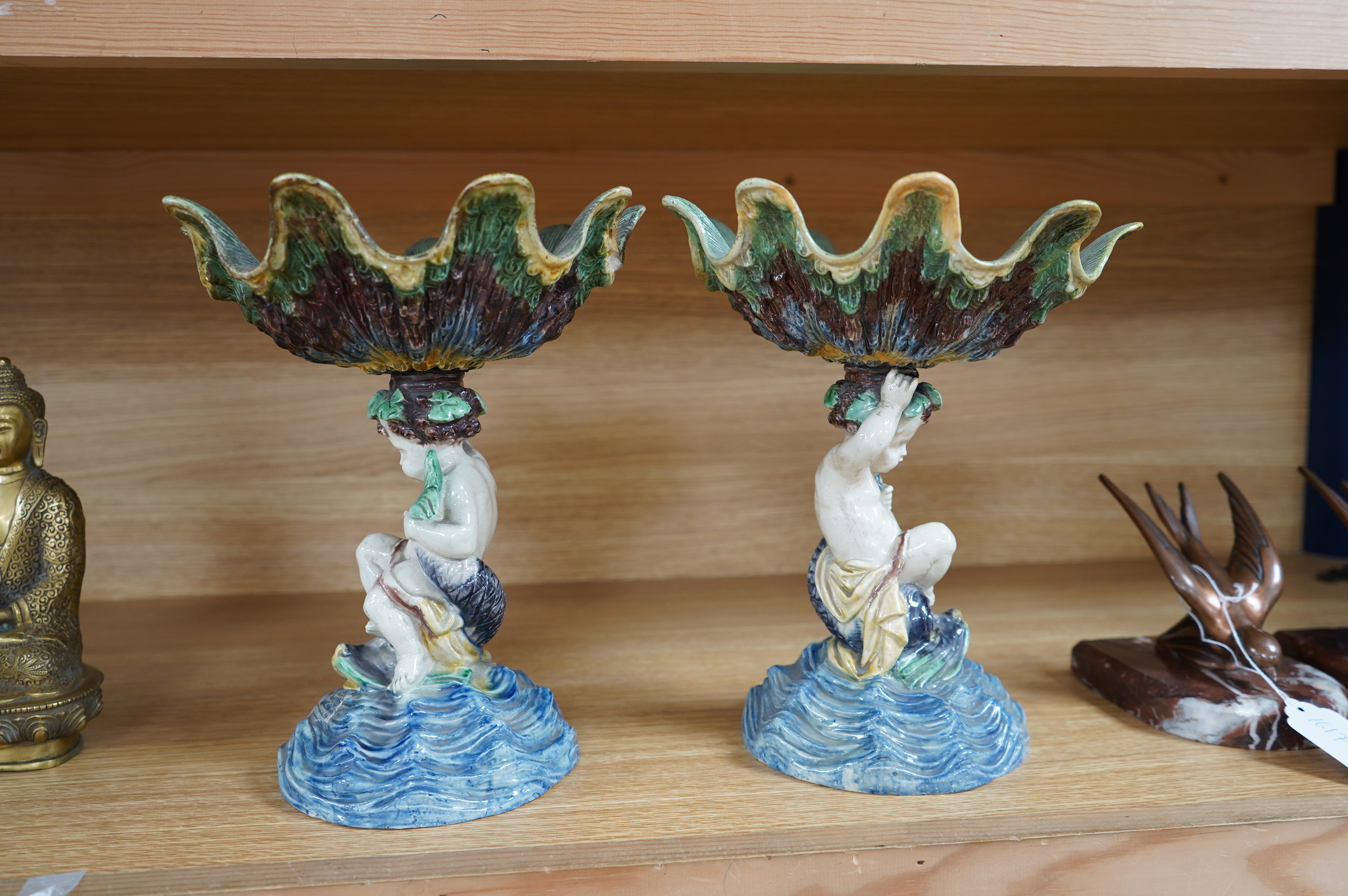 A pair of 19th century majolica comports with putti stems, 25cm. Condition - one repaired